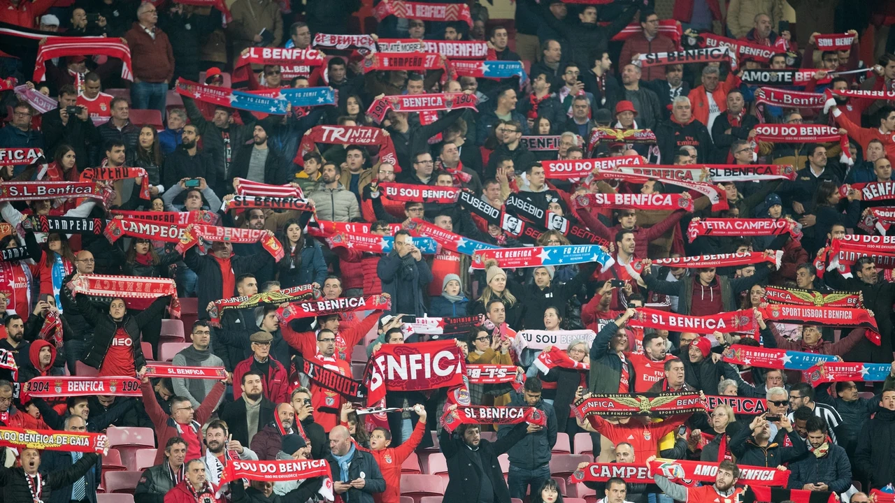 Filas de cadeiras cinzentas vazias numa bancada de estádio, à luz do dia